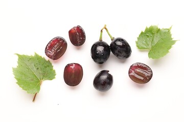Naklejka premium Fresh ripe grapes and green leaves on white background, flat lay