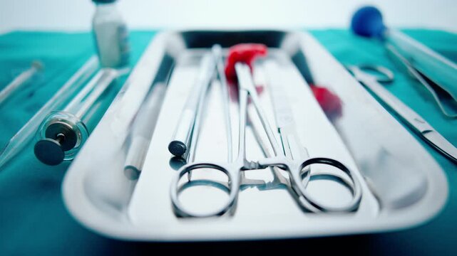 Sterile surgical instruments laid out in a steel tray. Operating room preparation, scalpels and forceps