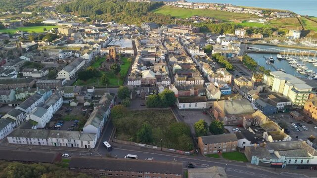 Aerial panoramic views of Whitehaven coastal town and civil parish. Town centre with architecture and main roads with moving vehicles in Sunrise, golden hour. Drone POV exploration of Devon County, UK