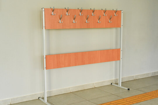 Wall-mounted coat rack for children with multiple metal hooks, wooden panels and bright indoor space, organized and practical setup for kids&rsquo; jackets and belongings