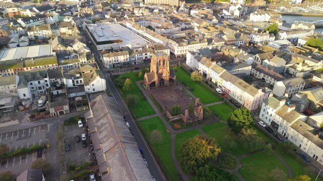 Aerial panoramic views of Whitehaven coastal town and civil parish. Town centre with architecture and main roads with moving vehicles in Sunrise, golden hour. Drone POV exploration of Devon County, UK