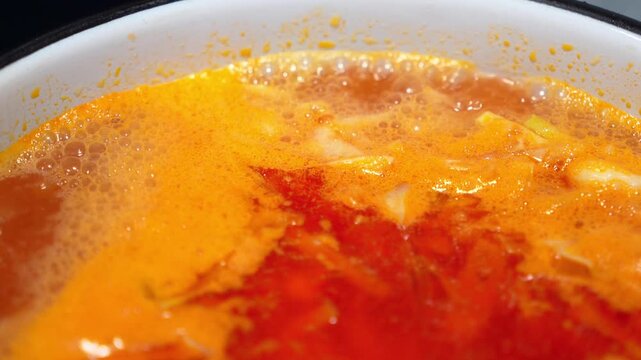 Traditional shchi cabbage soup cooking process texture with hot boiling broth bubbles inside an enamel pot indoors. Homemade eastern european recipe cuisine preparation scene, rustic kitchen menu. 