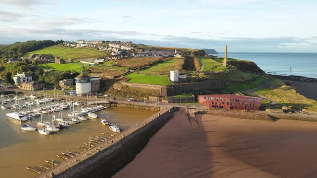 Aerial panoramic views of Whitehaven coastal town and civil parish. Marina and boats demonstration looking to the Irish sea in Sunrise, golden hour. Drone POV exploration of Devon County, England, UK.