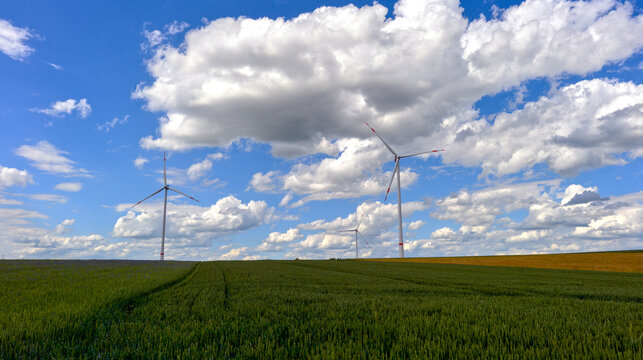 Windr&auml;der in einer gr&uuml;nen H&uuml;gellandschaft unter markantem Wolkenhimmel bei Spielberg, Brachttal, Hessen, Deutschland