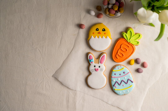 Easter festive colourful cookies: bunny, carrot, egg, chick with egg easter candies and bouquet of spring tulip flowers