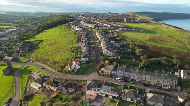 Aerial panoramic views of Whitehaven coastal town and civil parish. Town centre with architecture and main roads with moving vehicles in Sunrise, golden hour. Drone POV exploration of Devon County, UK