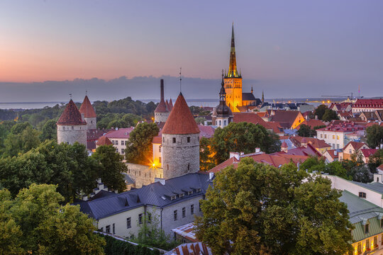 Walls of Tallinn and St Olaf church view from Toompea hill at sunset, Estonia. Evening illuminated medieval architecture