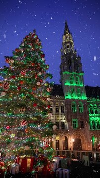 Christmas in Brussels, Belgium, concept with a illuminated, decorated tree in front of the City Hall at the Grand Place square with snow falling