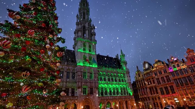 Christmas in Brussels, Belgium, concept with a illuminated, decorated tree in front of the City Hall at the Grand Place square with snow falling