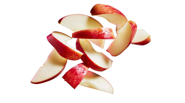 Isolated fresh vibrant red apple slices falling and scattering through the air, healthy organic snack