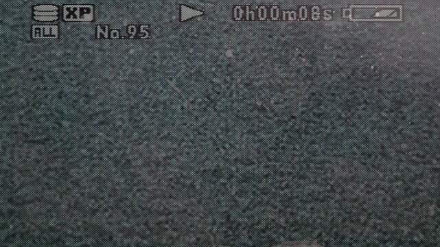 Close-up of a vintage digital camcorder playback display featuring recording information, timecode, battery indicator and analog-style visual noise.