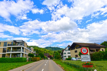 Fahrt am Ortseingang von Landikon mit Blick auf moderne Wohnhäuser und den Uetliberg, Kanton Zürich, Schweiz © Ilhan Balta