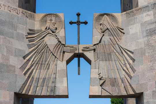 Close up of a carved stone relief depicting two haloed saints holding a cross with fine robe detail carved into the ancient facade of Etchmiadzin Cathedral, Etchmiadzin, Armenia