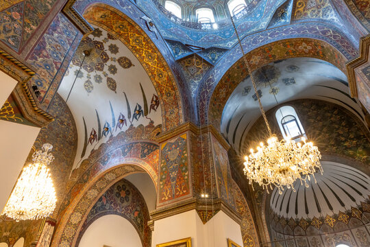 Large crowd of worshippers fills the cathedral during a religious service as clergy in vestments conduct mass beneath painted arches and chandeliers, Etchmiadzin, Armenia