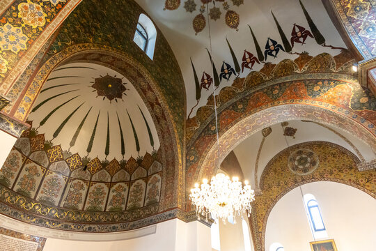 Ornately painted dome ceiling decorated with floral motifs and gold trim glows above a crystal chandelier viewed from a dramatic upward low angle shot, Etchmiadzin, Armenia