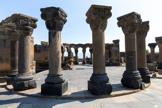 Rows of ornately carved basalt columns and arches rise from the ancient ruins of Zvartnots Cathedral against a backdrop of distant mountains, Etchmiadzin, Armenia