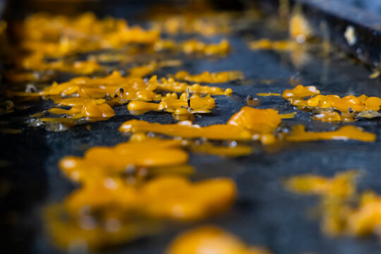 Melted yellow candle wax pools and hardens across dark stone inside Vahramashen Church forming an abstract textured pattern beside burnt wicks and shadow, Amberd, Armenia