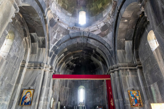 The stone nave and dome of Vahramashen Church lead toward a candlelit altar adorned with icons of the Virgin Mary beneath a symmetrical vaulted ceiling, Amberd, Armenia