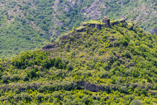 Visitor standing at the open entrance door of the medieval stone facade of Dsevank Church beneath a carved cross and gothic arch weathered with moss and age, Haghpat, Armenia
