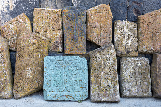 Khachkar stone crosses with ornate religious carvings and ancient symbolic patterns mounted on a weathered turquoise wall at Sevanavank Monastery, Sevanavank, Armenia