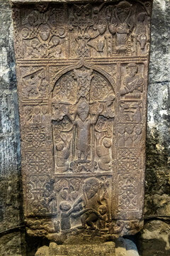 Carved khachkar stone cross depicting a saint figure with intricate weathered religious detail and ancient craftsmanship at the historic Sevanavank Monastery, Sevanavank, Armenia