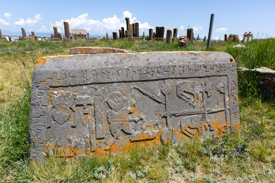 Inscribed khachkar stone standing among countless weathered stelae forming a dense ancient stone forest with Armenian script at Noratus medieval cemetery, Noratus, Armenia