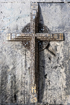Wooden cross covered with small nails and sequins as votive offerings hangs mounted on a stone wall at the ancient monastery in Gegharkunik Province, Artsvanist, Armenia
