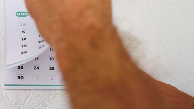 Close-up of male hands tearing off October page from a wall calendar, revealing November 2026 page with the marked Black Friday date on November 27. Global shopping and big sales discount concept