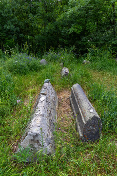 Two ancient Jewish gravestones rest side by side in the grass with small memorial stones placed on top as a quiet traditional gesture of remembrance and mourning, Eghegis, Armenia