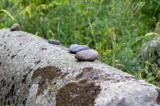 Small pebbles placed on top of a weathered ancient Jewish gravestone covered in lichen and moss as a quiet mark of remembrance and mourning tradition, Eghegis, Armenia