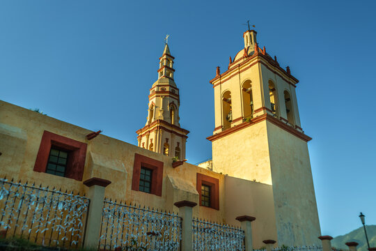 Historic Santiago Apostol church with twin bell towers and colonial architecture under a clear blue sky in Santiago, Nuevo Leon, Mexico.