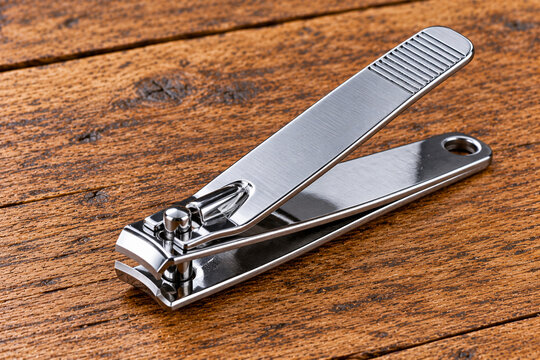 Stainless steel nail clipper resting on wooden table surface