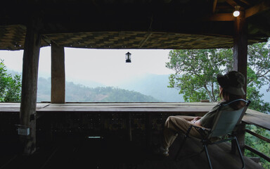 Fototapeta premium A woman sitting on wooden terrace and looking at nature views