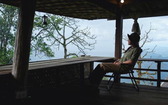 A woman sitting on wooden terrace and looking at nature views