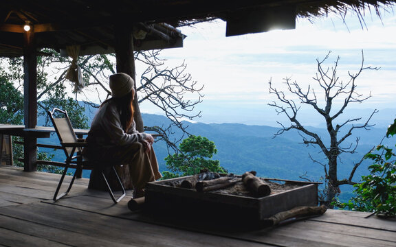 Rear view of a woman sitting on wooden terrace and looking at nature views