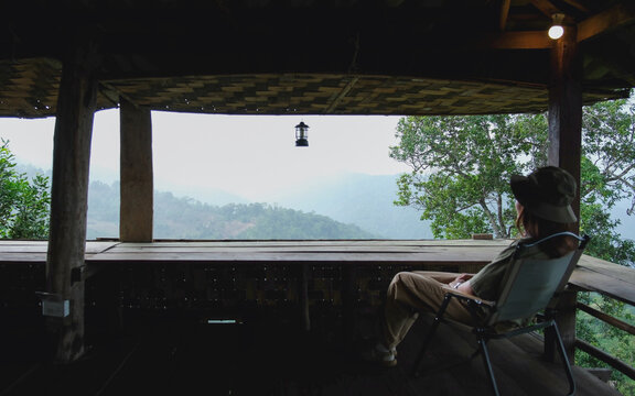 A woman sitting on wooden terrace and looking at nature views