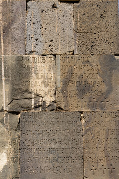 Ancient Armenian inscriptions remain carved into the weathered lichen covered stone walls of Tatev Monastery preserving centuries of history and culture, Tatev, Armenia