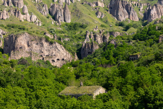 Suspension bridge stretching across a lush green forested canyon and ravine near the ancient troglodyte cave village carved into the rocky cliffside, Khndzoresk, Armenia