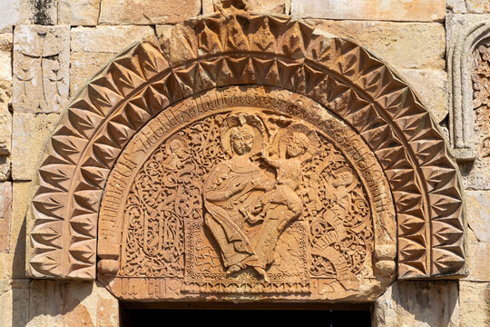 Richly carved stone tympanum of the enthroned Madonna and Christ child flanked by angels and Armenian script at Astvatsatsin church and monastery, Noravank, Armenia