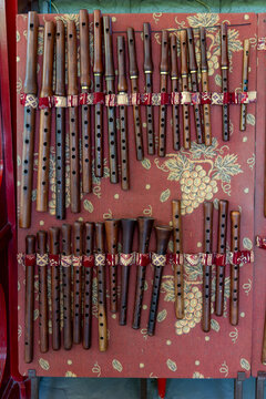 Rows of handmade duduk flutes carved from apricot wood hang on display inside a traditional workshop decorated with a grapevine motif textile pattern, Yerevan, Armenia
