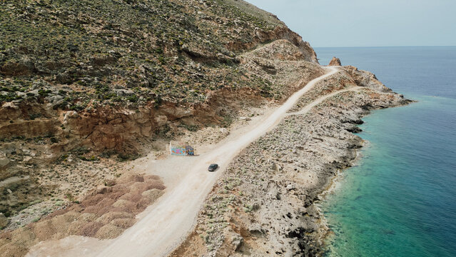 Aerial view of narrow dirt off road leading to Balos beach along rocky coastline and turquoise Mediterranean sea in Crete island Greece
