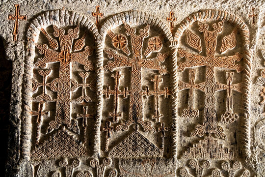 Close up of ornately carved stone crosses known as khachkars decorating the ancient wall of Geghard monastery with intricate interlace and geometric patterns, Geghard, Armenia