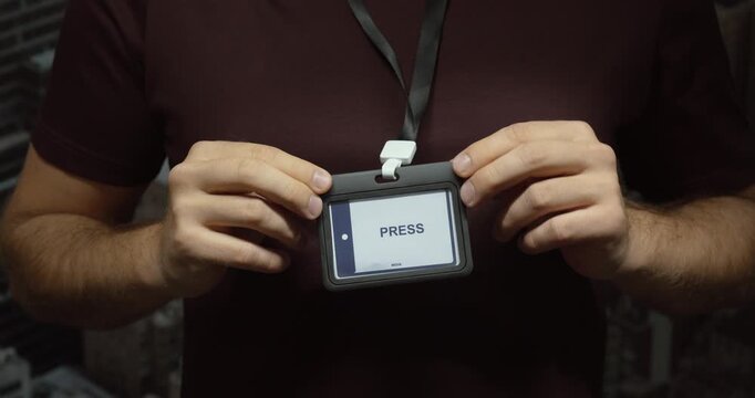 Close-up of a person displaying a press identification badge on a lanyard. Concept for journalism, media access, reporting and news coverage.
