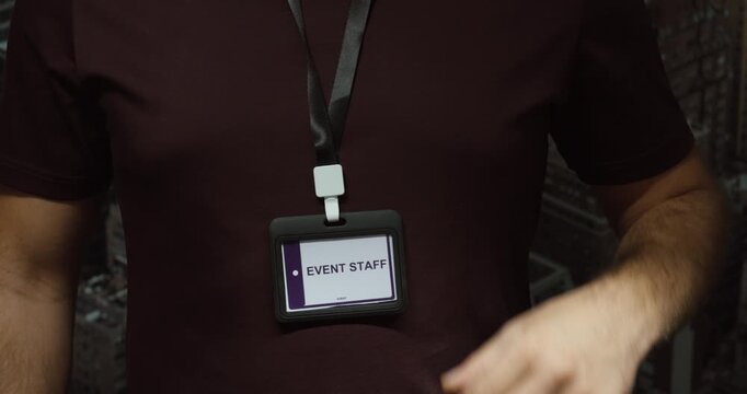 Close-up of a person displaying an event staff identification badge on a lanyard. Concept for event management, crew access, security and organization.