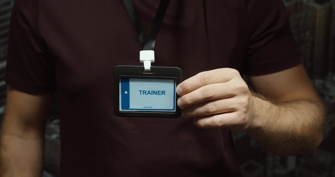 Close-up of a person displaying a trainer identification badge on a lanyard. Concept for professional training, coaching, education and workplace instruction.