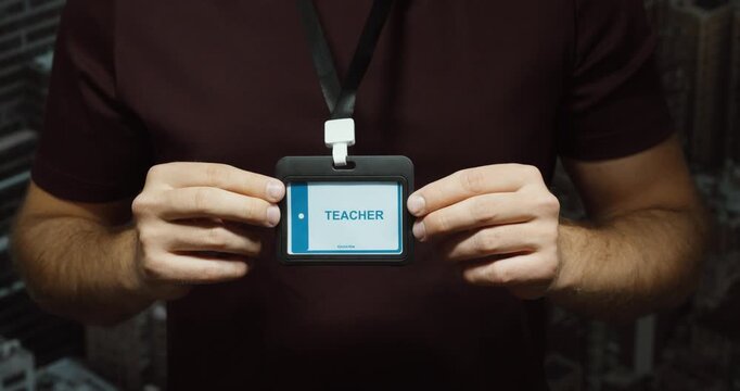 Close-up of a person displaying a teacher identification badge on a lanyard. Concept for education, school staff, teaching and professional identity.