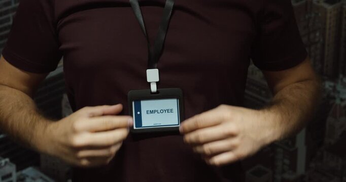 Close-up of an employee putting on and adjusting an identification badge lanyard. Concept for starting work, workplace access and professional identity.