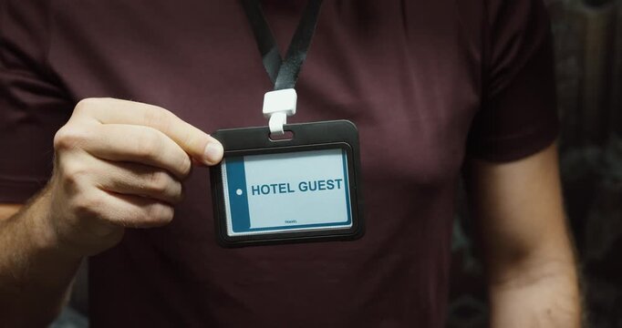 Close-up of a person displaying a hotel guest identification badge on a lanyard. Concept for hospitality, accommodation, visitor access and guest services.