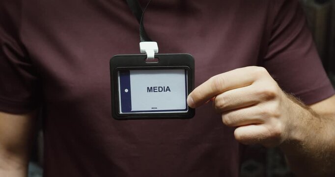 Close-up of a person displaying a media identification badge attached to a lanyard. Concept for journalism, press access, reporting and official accreditation.