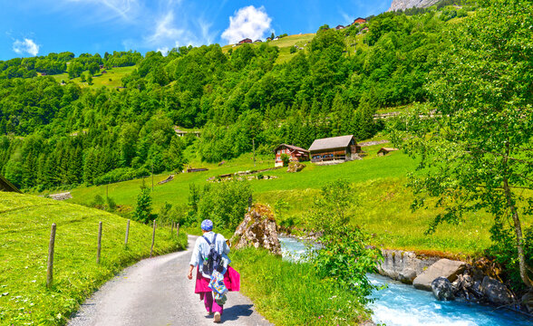 Untersch&auml;chen, Sch&auml;chental, Kanton Uri, Schweiz: Eine Wanderin mit Rucksack geht auf einem Schotterweg am klaren Sch&auml;chenbach vorbei talaufw&auml;rts im Sommer